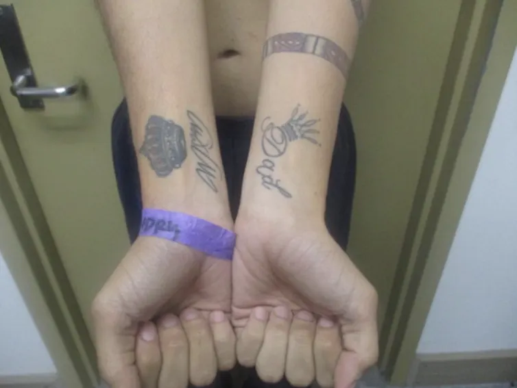 Two outstretched arms with a tattoo on each wrist, one reading 'Mom' and the other reading 'Dad.'