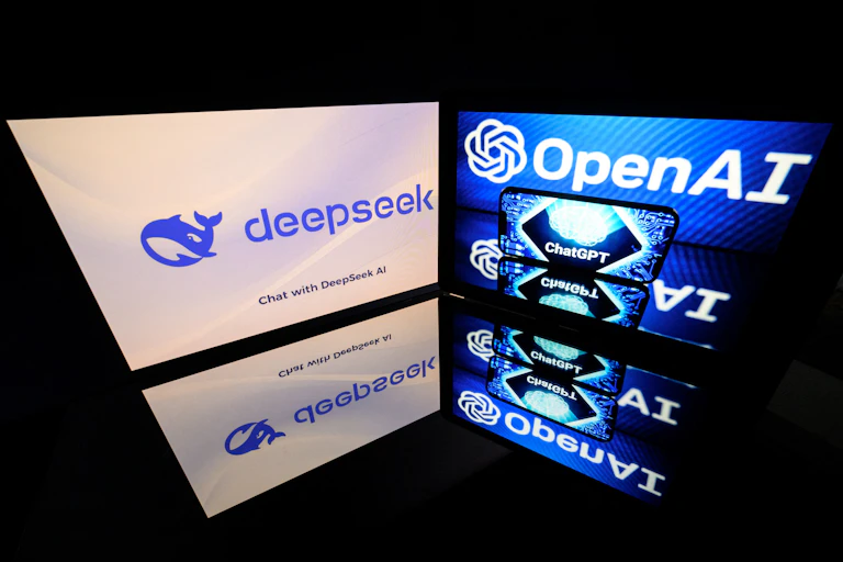 two monitors at a close angle to each other displaying logos and text, which are reflected on a surface
