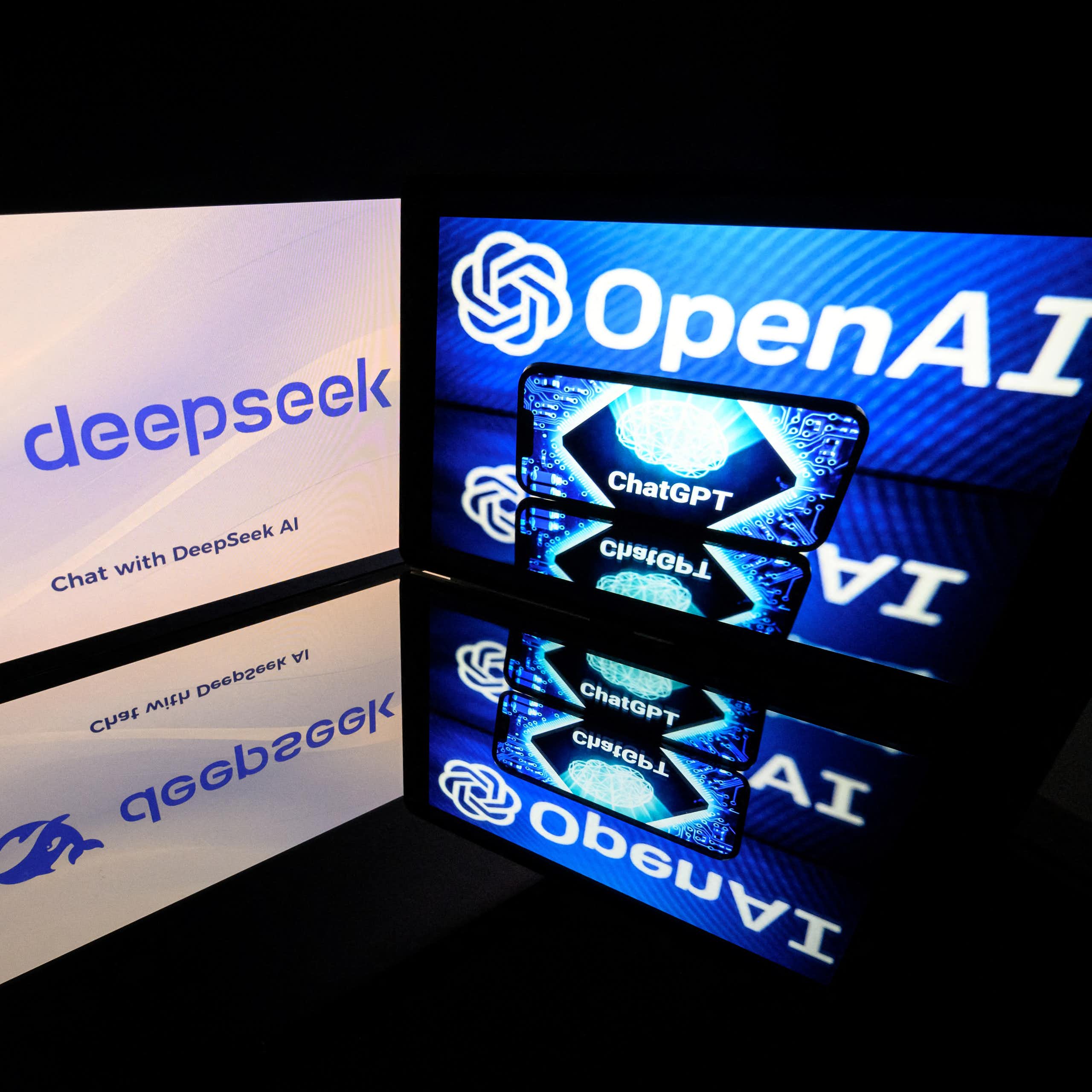 two monitors at a close angle to each other displaying logos and text, which are reflected on a surface