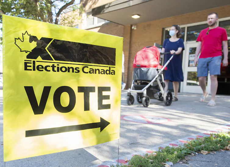 A man and a woman pushing a stroller leaving a polling station