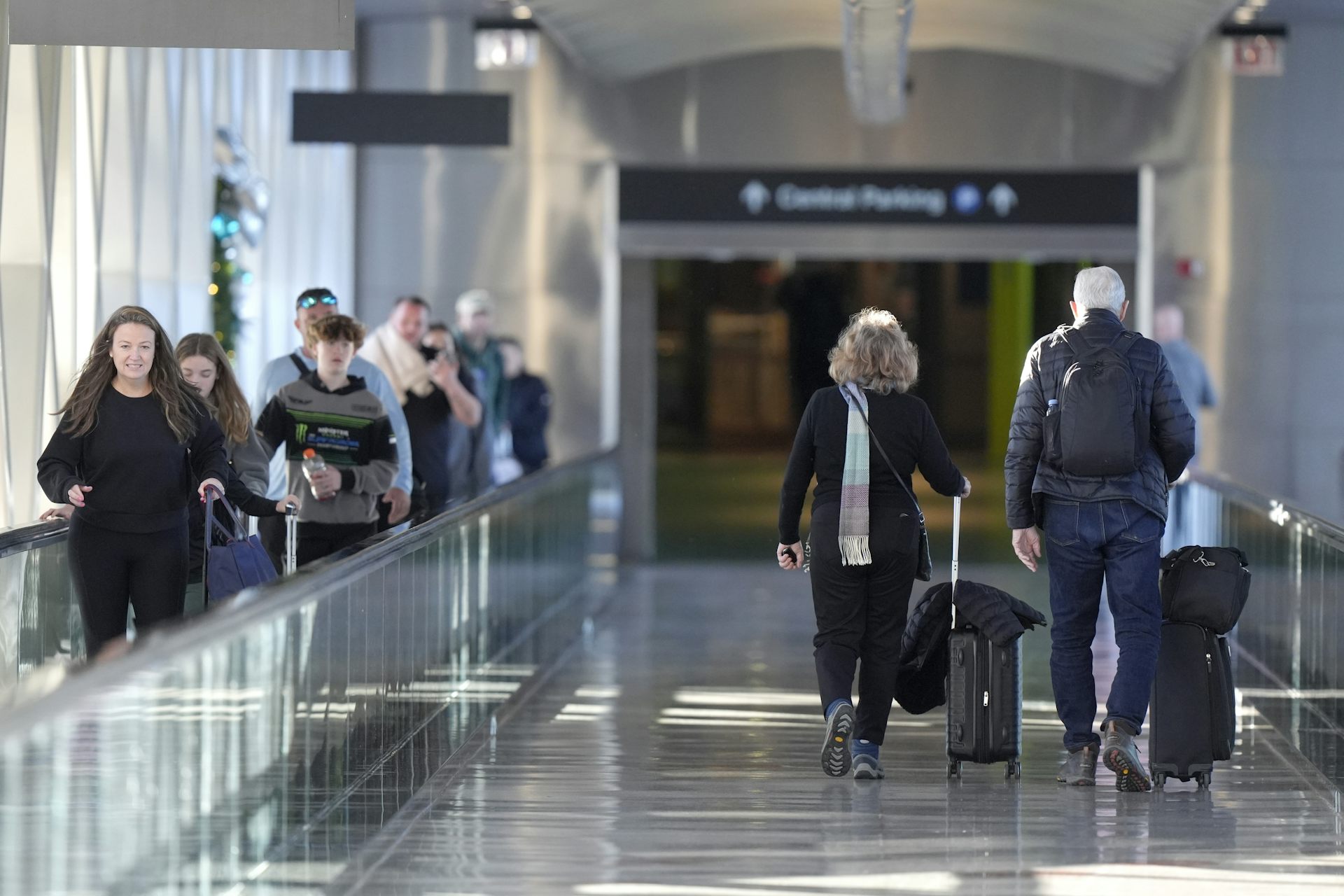 Personnes utilisant un trottoir roulant, marchant et tirant des valises dans un aéroport