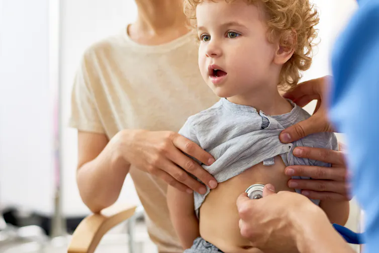 A doctor examines a small boy with a stethoscope.