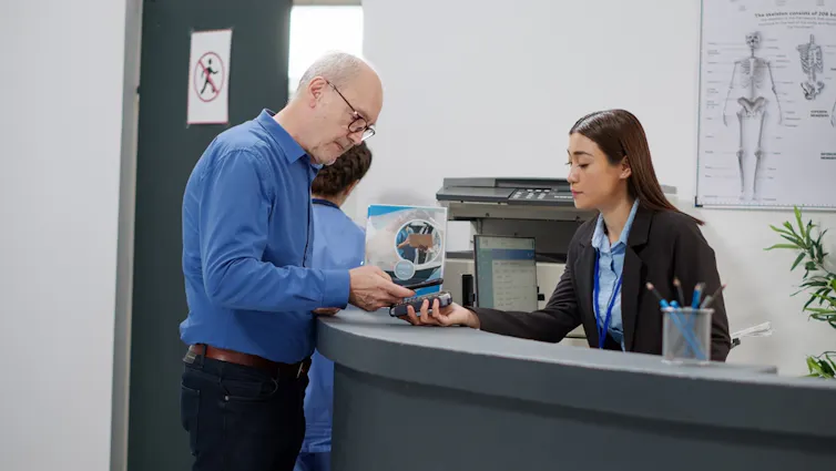 Elderly man paying for health care at doctor's reception