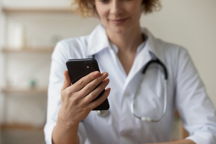 Female doctors with stethoscope around neck looking at smartphone