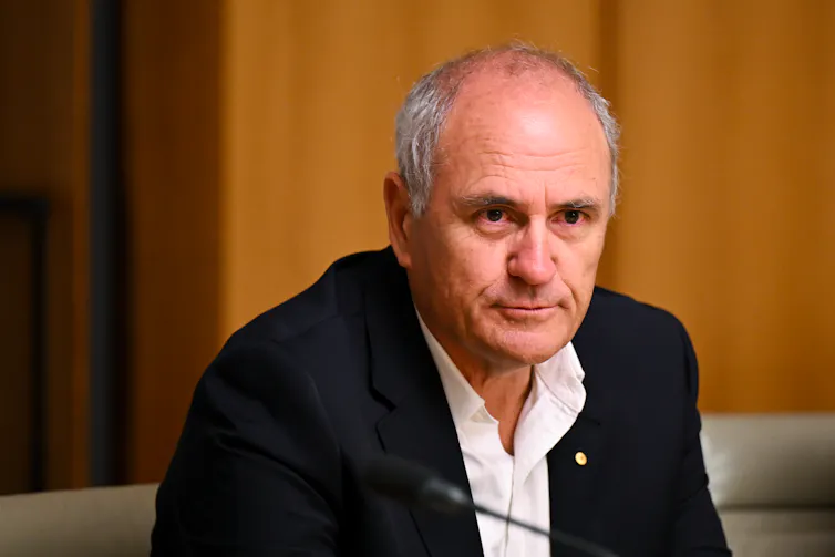 Former Treasury Secretary Ken Henry in a jacket and open necked shirt sitting in a wood panelled room with a pensive look on his face