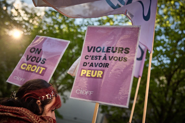 Une manifestante tient une pancarte sur laquelle on peut lire « Violeurs, c'est à votre tour d'avoir peur » (à droite) lors d'une manifestation à l'appel de plusieurs associations féministes près de l'Assemblée nationale française en soutien à la redéfinition pénale du viol intégrant la notion de consentement alors que la redéfinition est débattue à l'Assemblée nationale, à Paris, le 1er avril 2025.