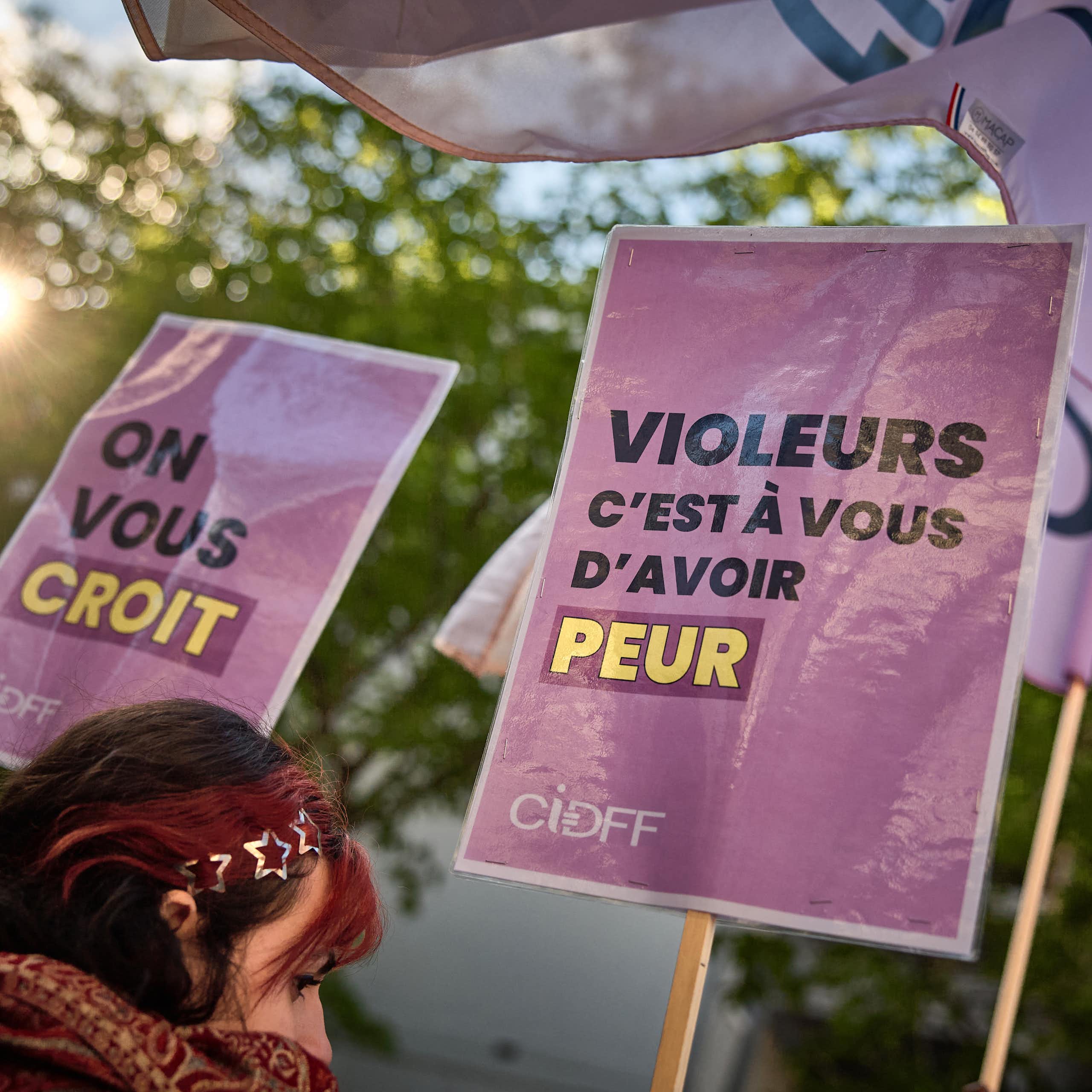 Une manifestante tient une pancarte sur laquelle on peut lire « Violeurs, c'est à votre tour d'avoir peur » (à droite) lors d'une manifestation à l'appel de plusieurs associations féministes près de l'Assemblée nationale française en soutien à la redéfinition pénale du viol intégrant la notion de consentement alors que la redéfinition est débattue à l'Assemblée nationale, à Paris, le 1er avril 2025.