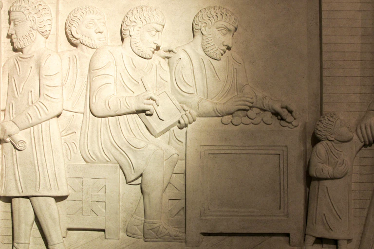 A low relief depicts ancient Roman commerce activities.