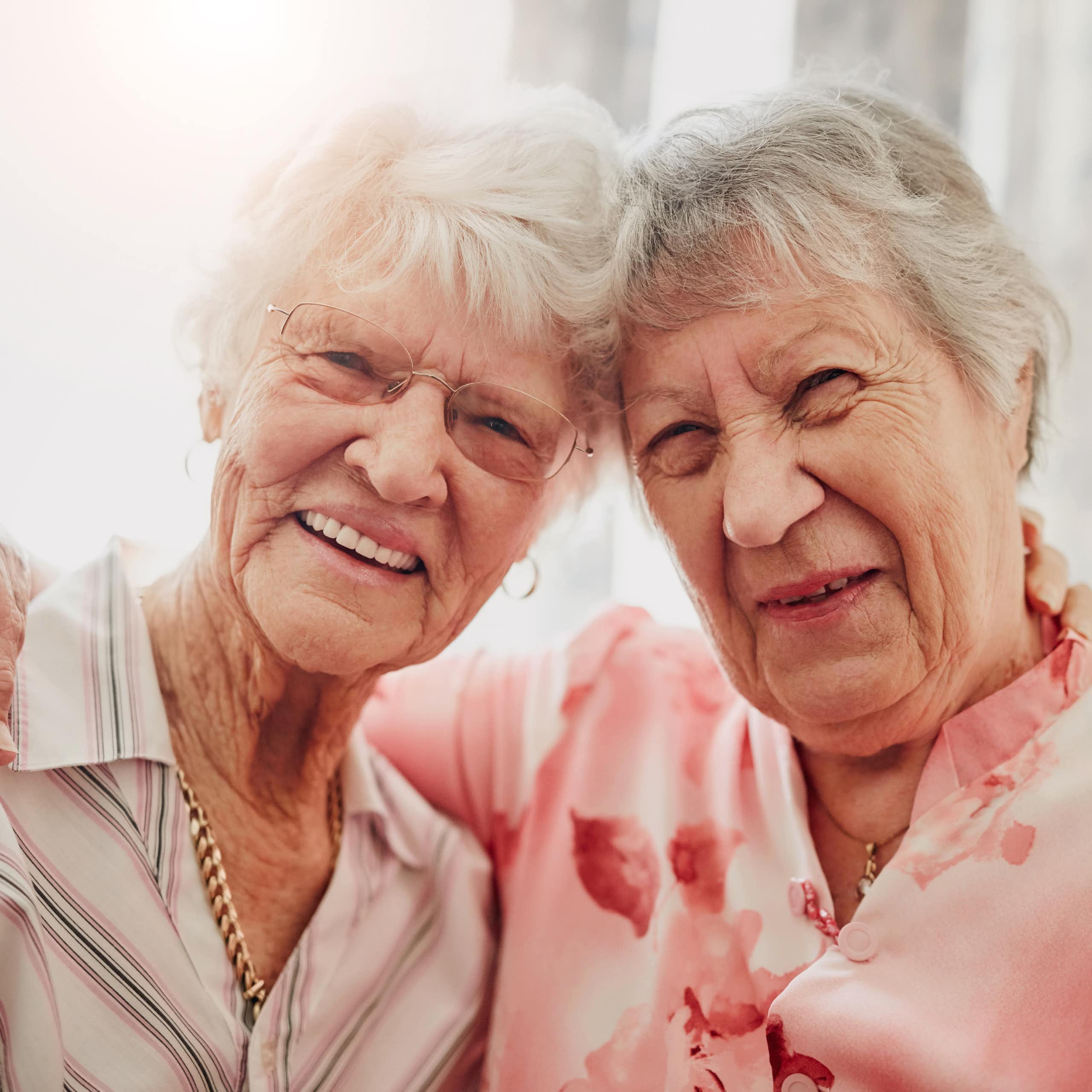 Deux femmes âgées se tiennent pas le bras et sourient.