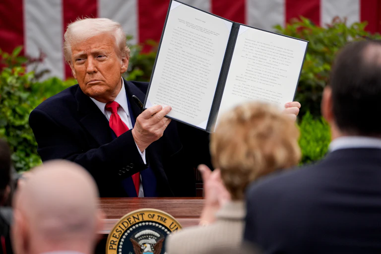 us president donald trump holds up a signed executive order outlining new tariffs