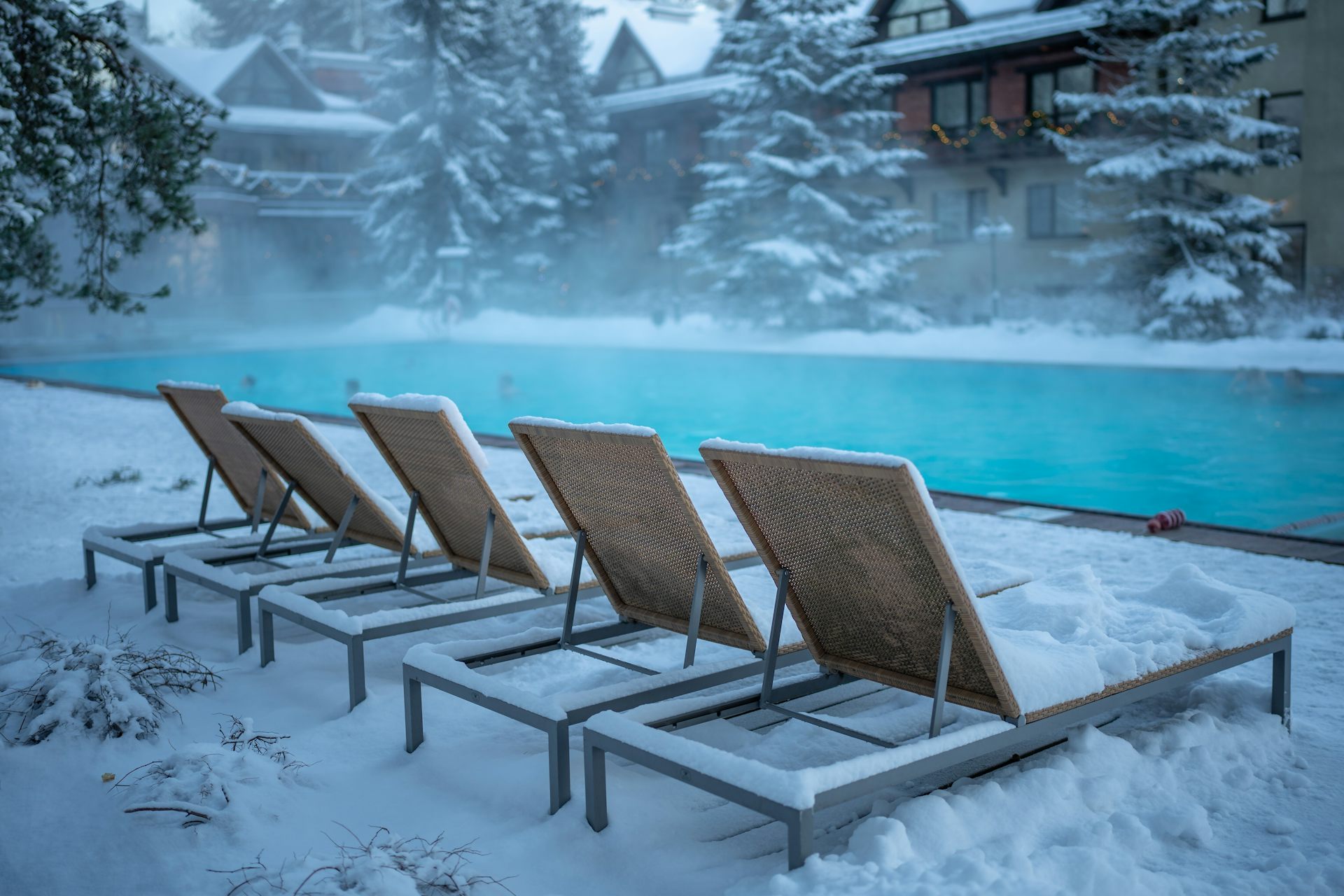 Des chaises longues longent une piscine en hiver.