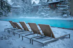 Des chaises longues longent une piscine en hiver.