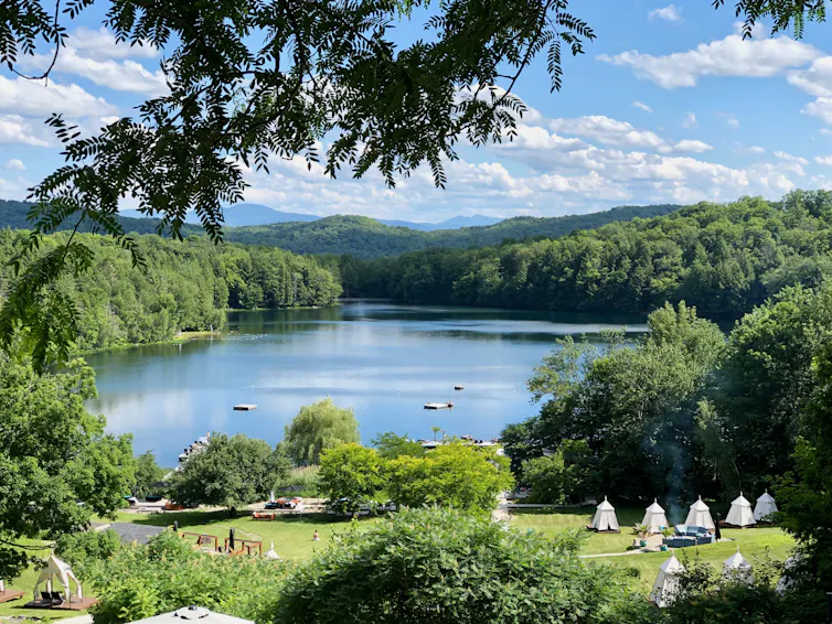 Un lac entouré d'une forêt et de tipis