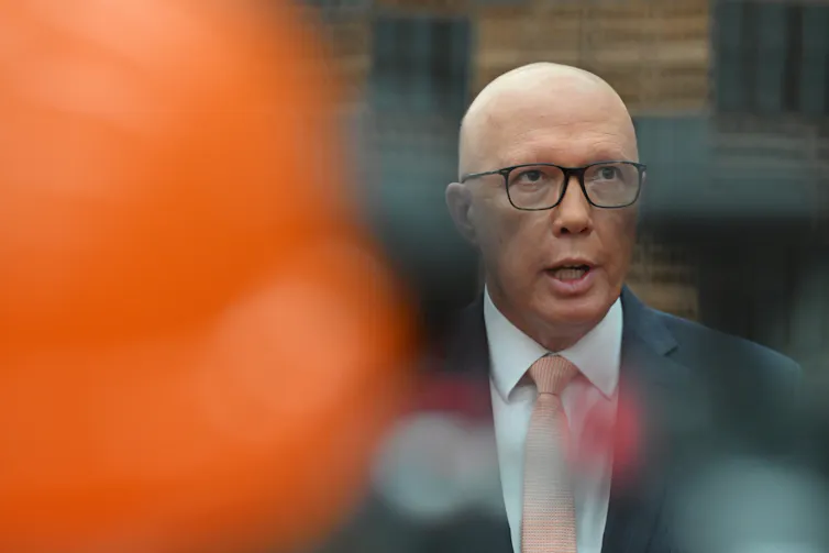 Peter Dutton speaks behind some out of focus colours