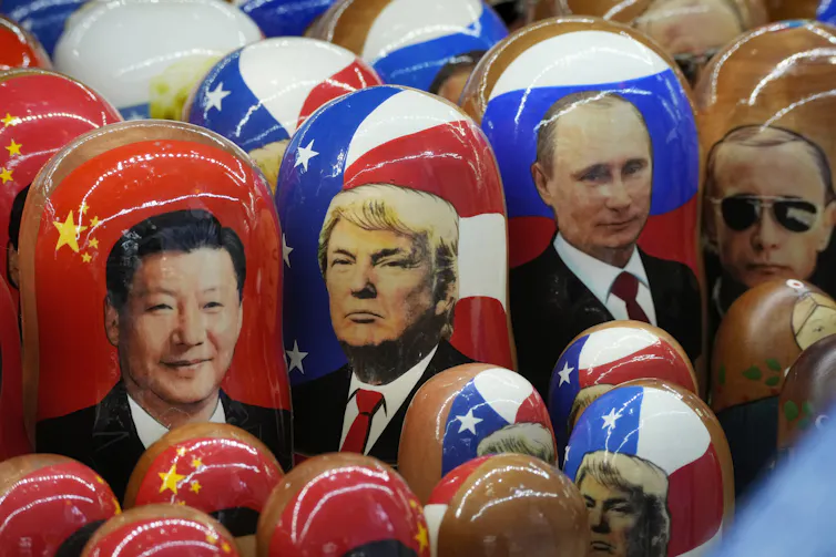 Red white and blue babushka dolls bearing the images of Xi Jinping, Donald Trump and Vladimir Putin