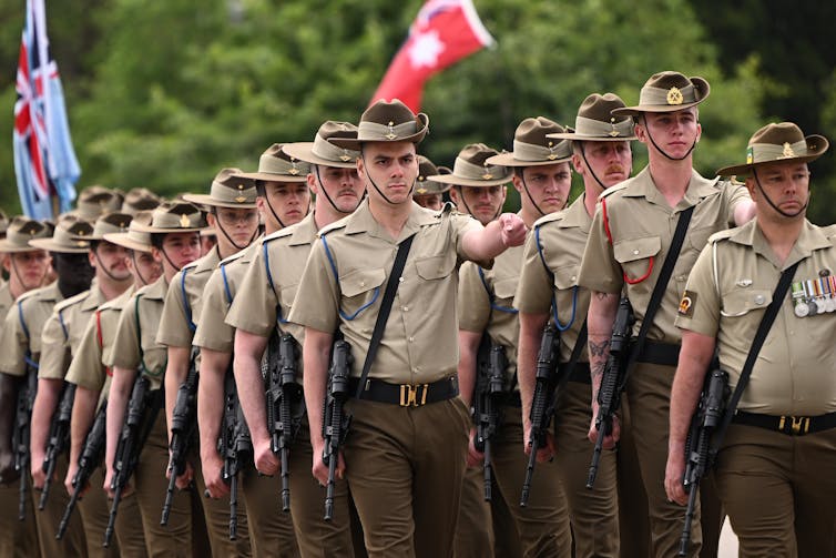 Two columns of uniformed Australian soldiers marching on a parade ground