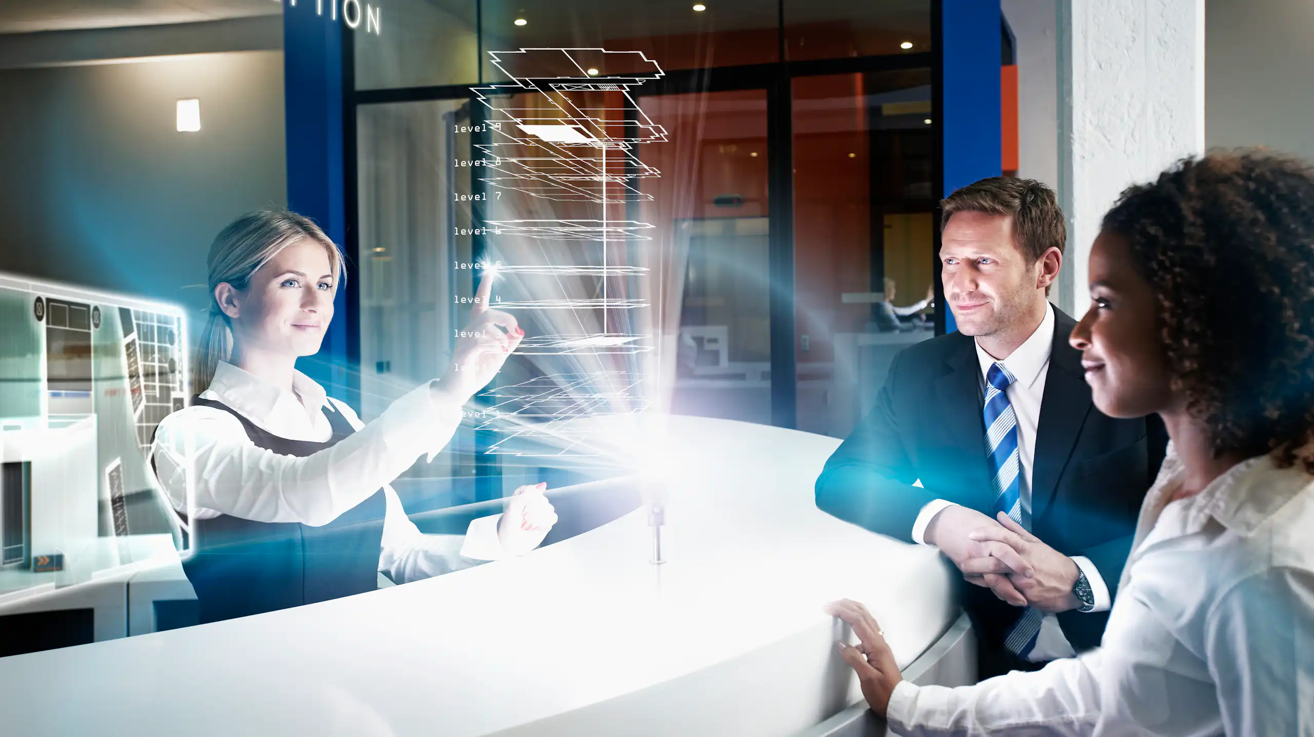 A woman behind a hotel counter interacts with two guests.