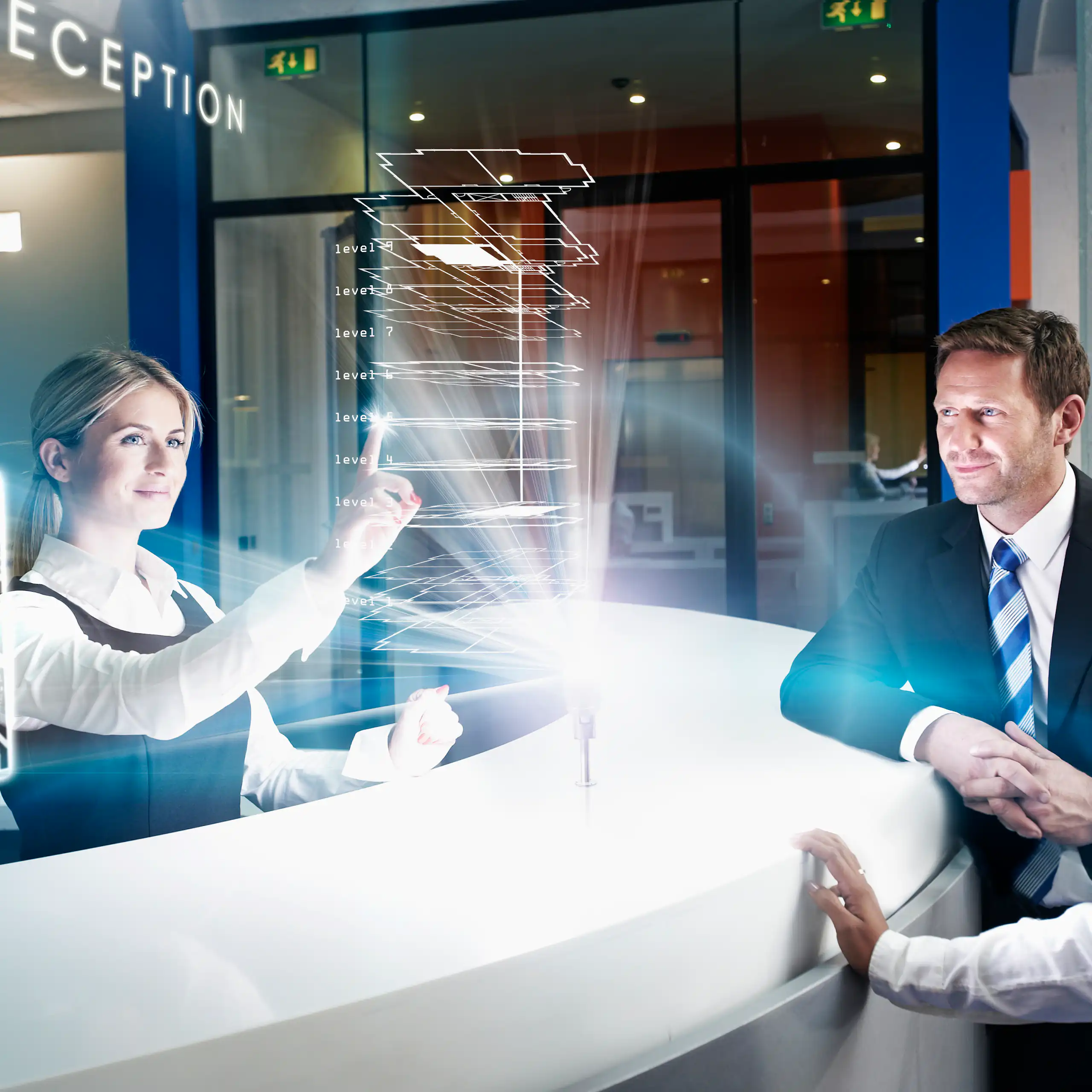 A woman behind a hotel counter interacts with two guests.