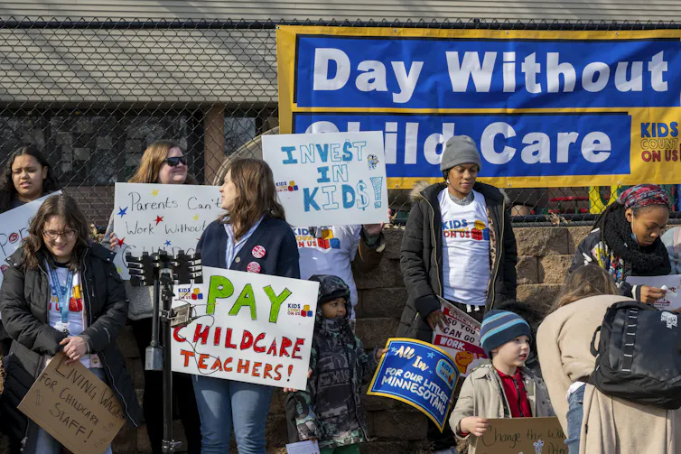 People hold signs at a rally to make child care more affordable.