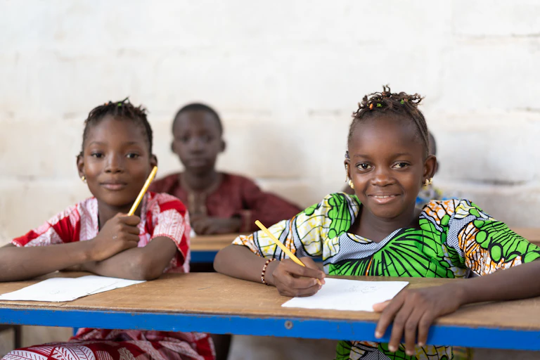 Girls sitting at desks with paper and pencils