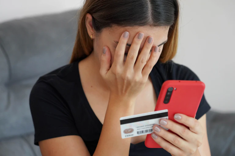 Woman holds face in disbelief as she looks at her bank account