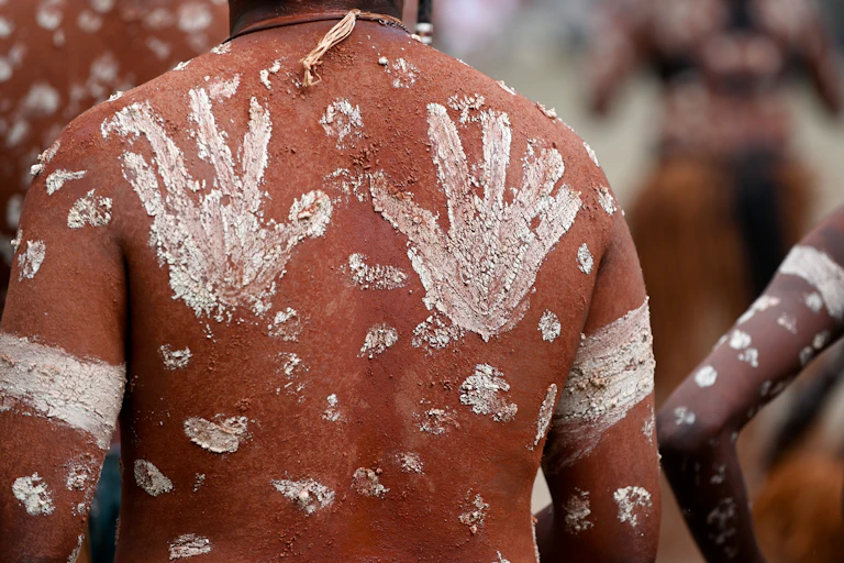 An Indigenous man's back with ceremonial hand markings
