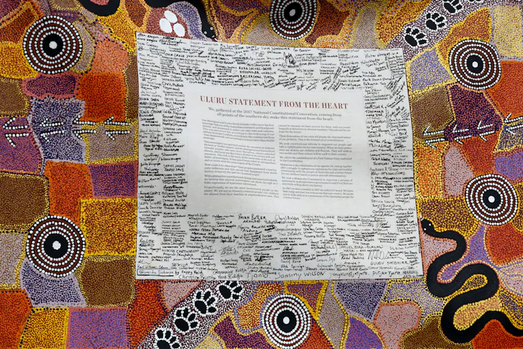 A multicoloured piece of Indigenous art with the Uluru Statement from the Heart in the centre