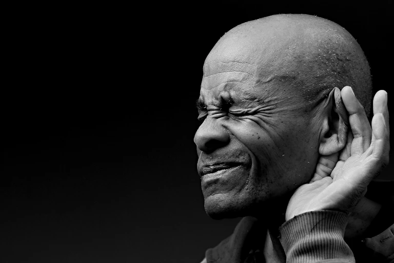 Black and white photo of a man holding his hand to his ear