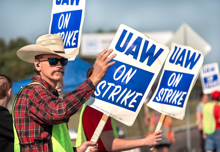 Man in a cowboy hat holding a sign saying 'UAW on strike'.