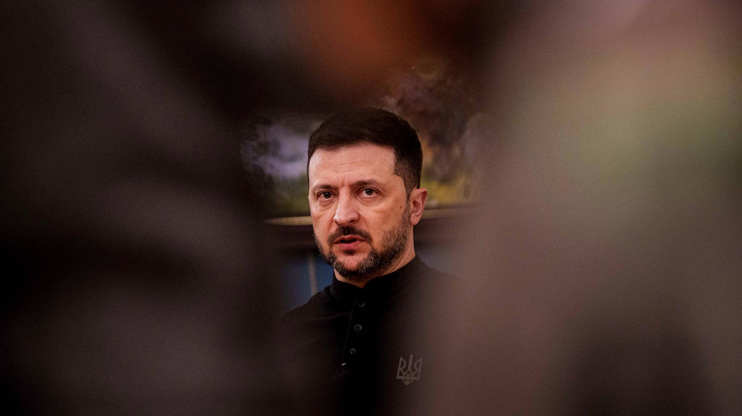 A man's face framed by blurry objects on either side.