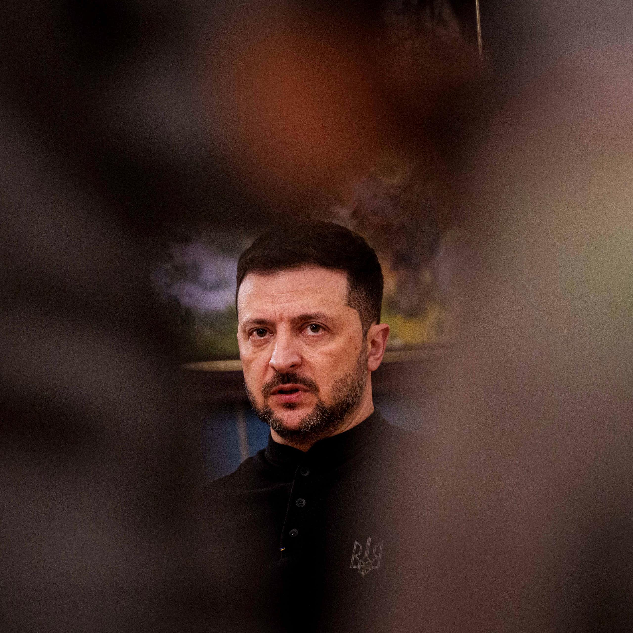 A man's face framed by blurry objects on either side.