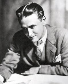 F. Scott Fitzgerald writing while wearing a suit.