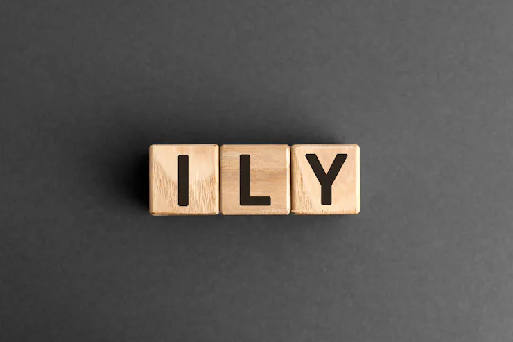 Three wooden blocks with one black letter on each block – 'I,' 'L' and 'Y.'