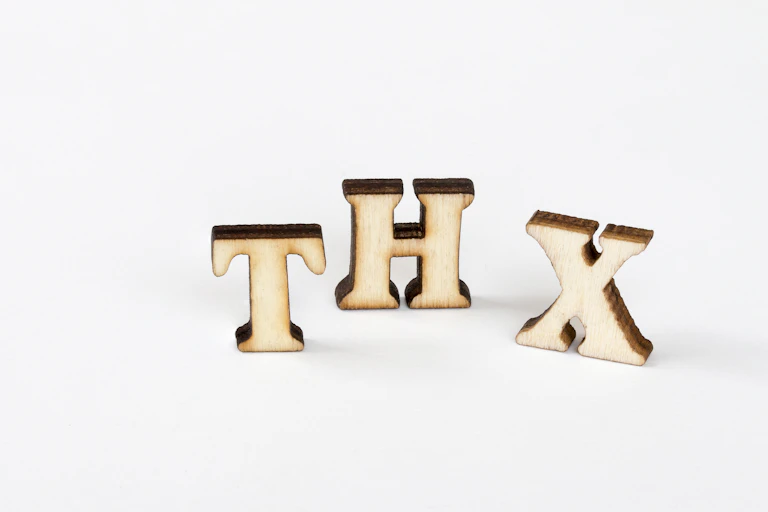 Three wooden cutouts of the letters 'T,' 'H' and 'X.'