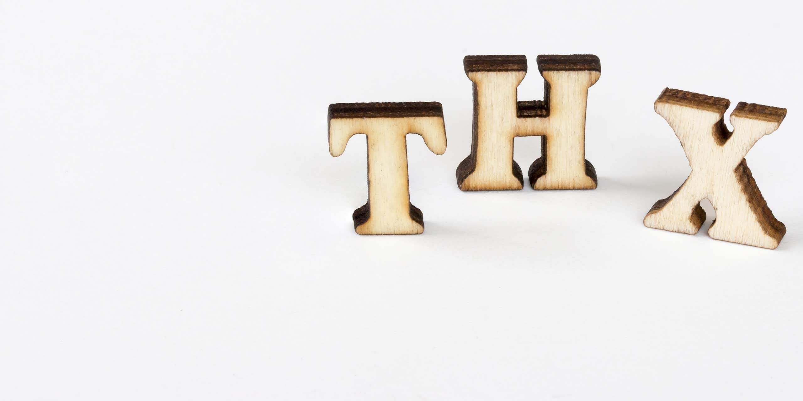Three wooden cutouts of the letters 'T,' 'H' and 'X.'
