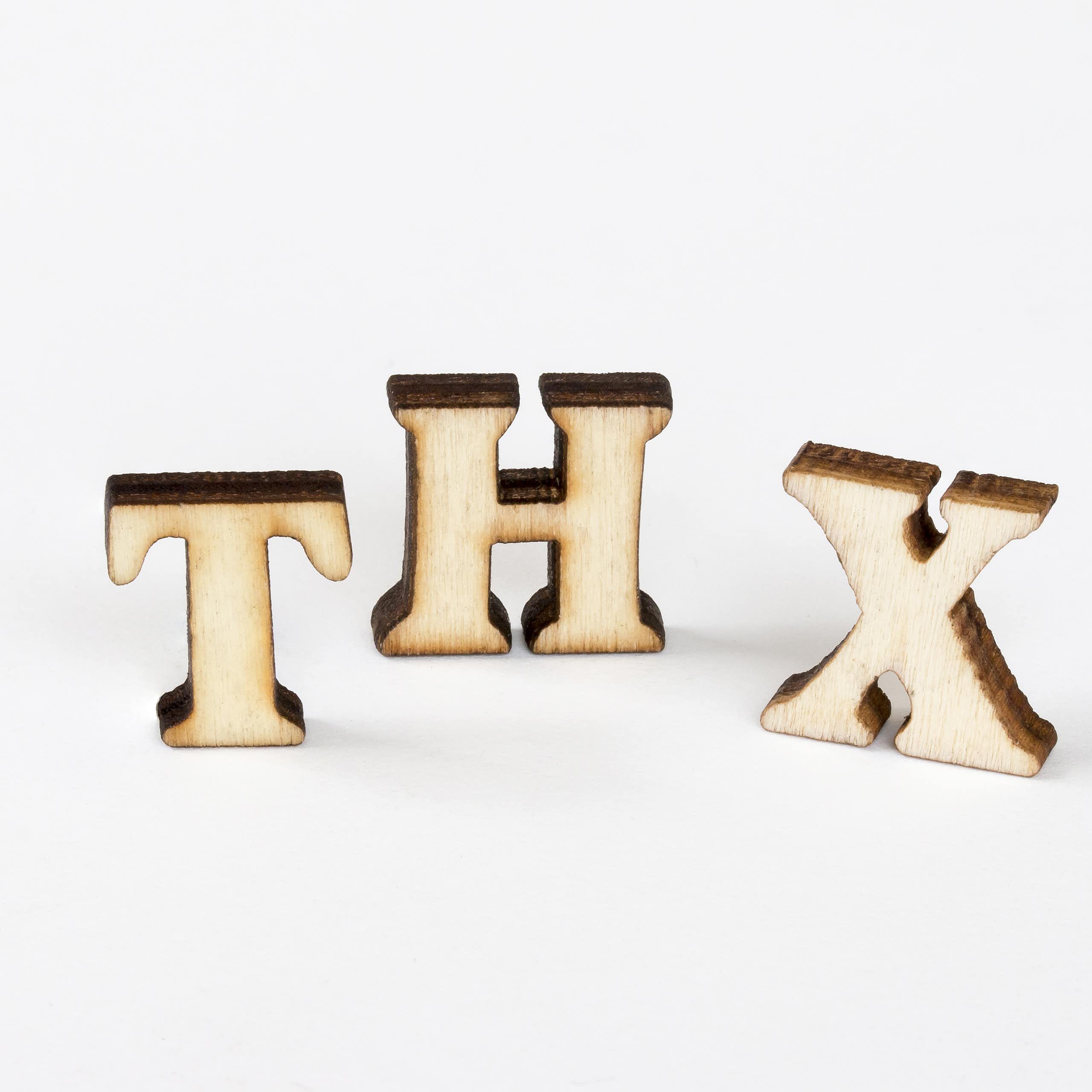 Three wooden cutouts of the letters 'T,' 'H' and 'X.'