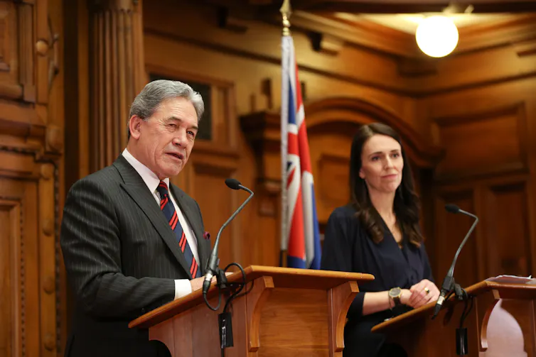 Winston Peters and Jacinda Ardern at podiums.
