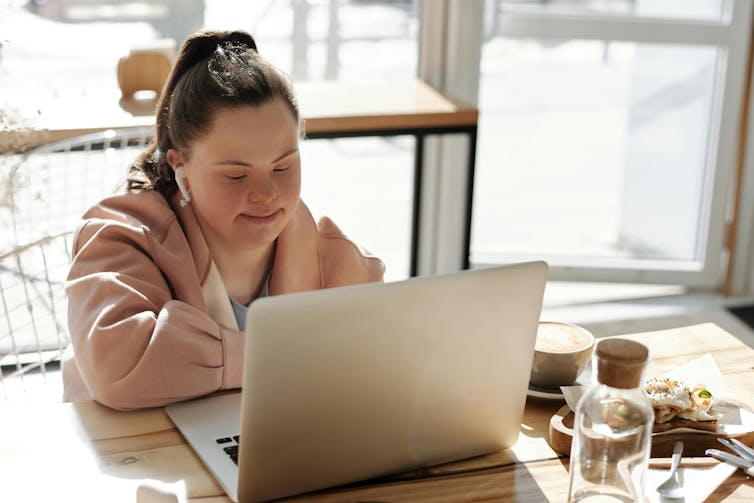 A Down Syndrome girl at a laptop with breakfast