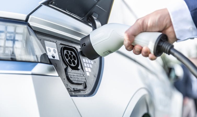 woman hand charging electric car.