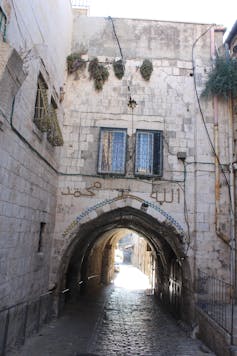 Calle empedrada que pasa bajo un arco en el casco histórico de la ciudad de Jerusalén.