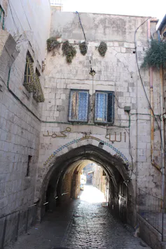 Calle empedrada que pasa bajo un arco en el casco histórico de la ciudad de Jerusalén.