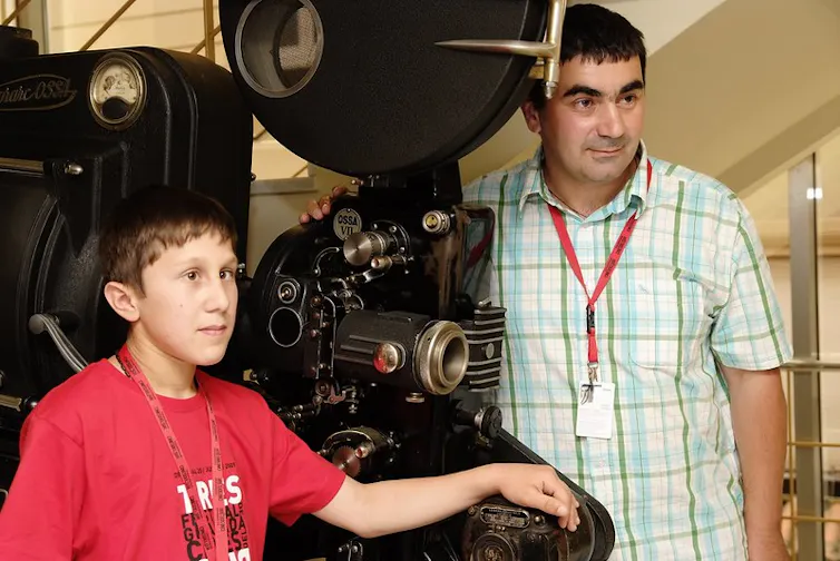 Niño y adulto al lado de la cámara de la película.