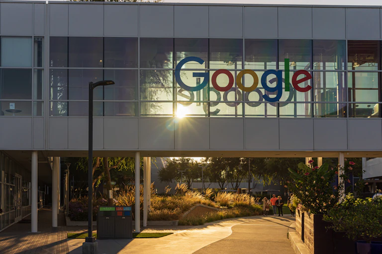 le siège social de google avec le logo sur une vitre avec derrière un soleil qui semble couchant