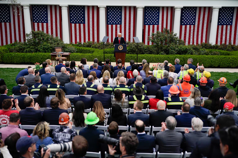 us president donald trump announcing liberation day tariffs as blue-collar workers look on.