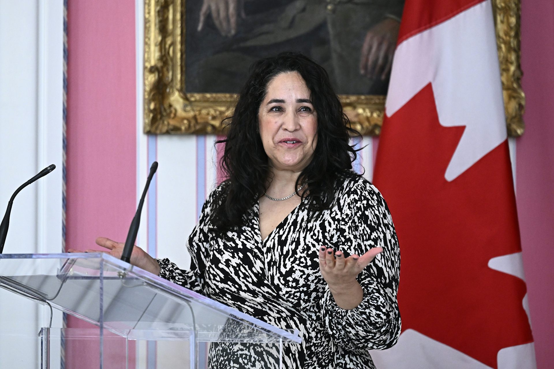 A woman at a podium with Canadian flag behind her.