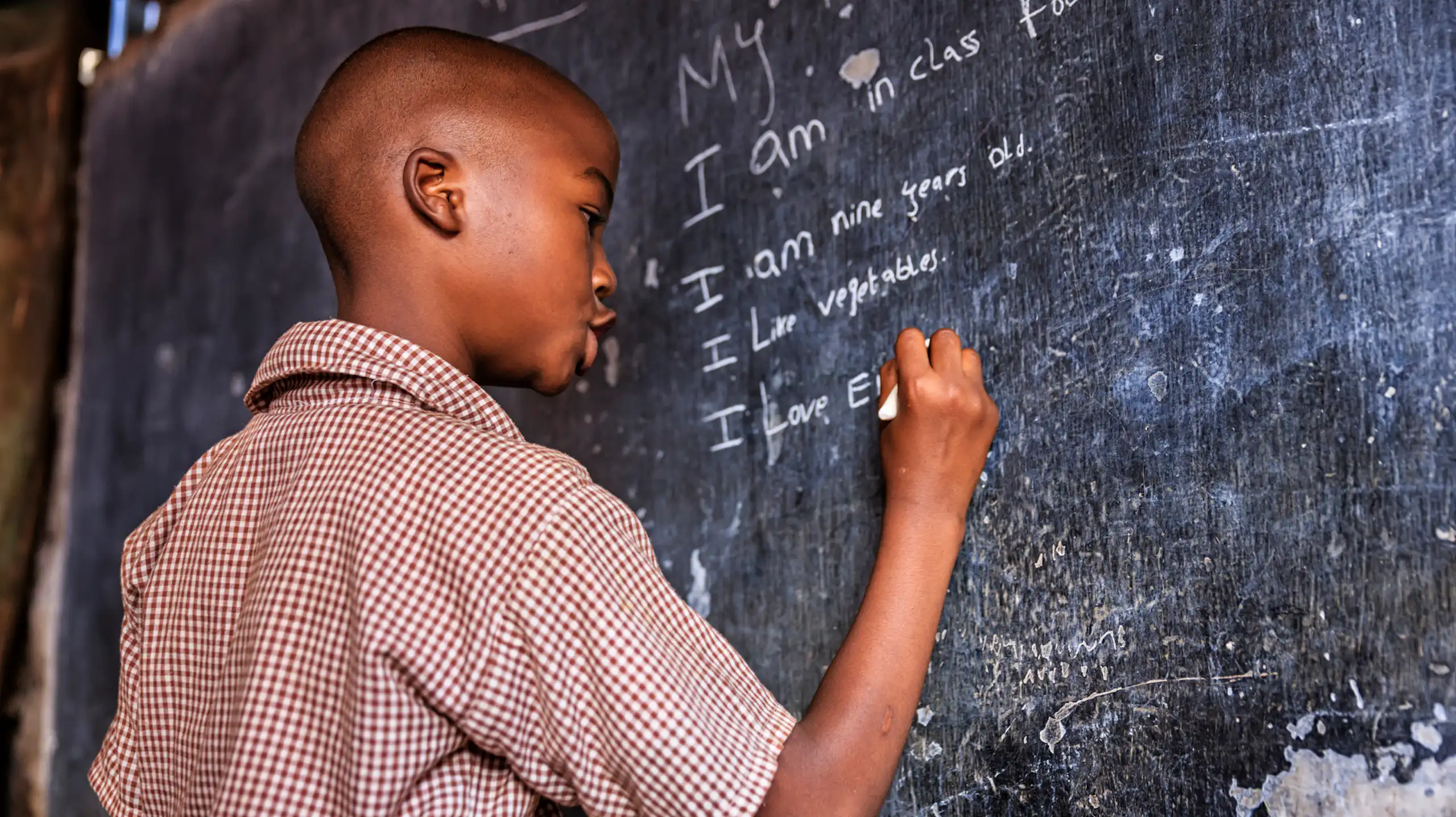 A boy writing on a chalkboard