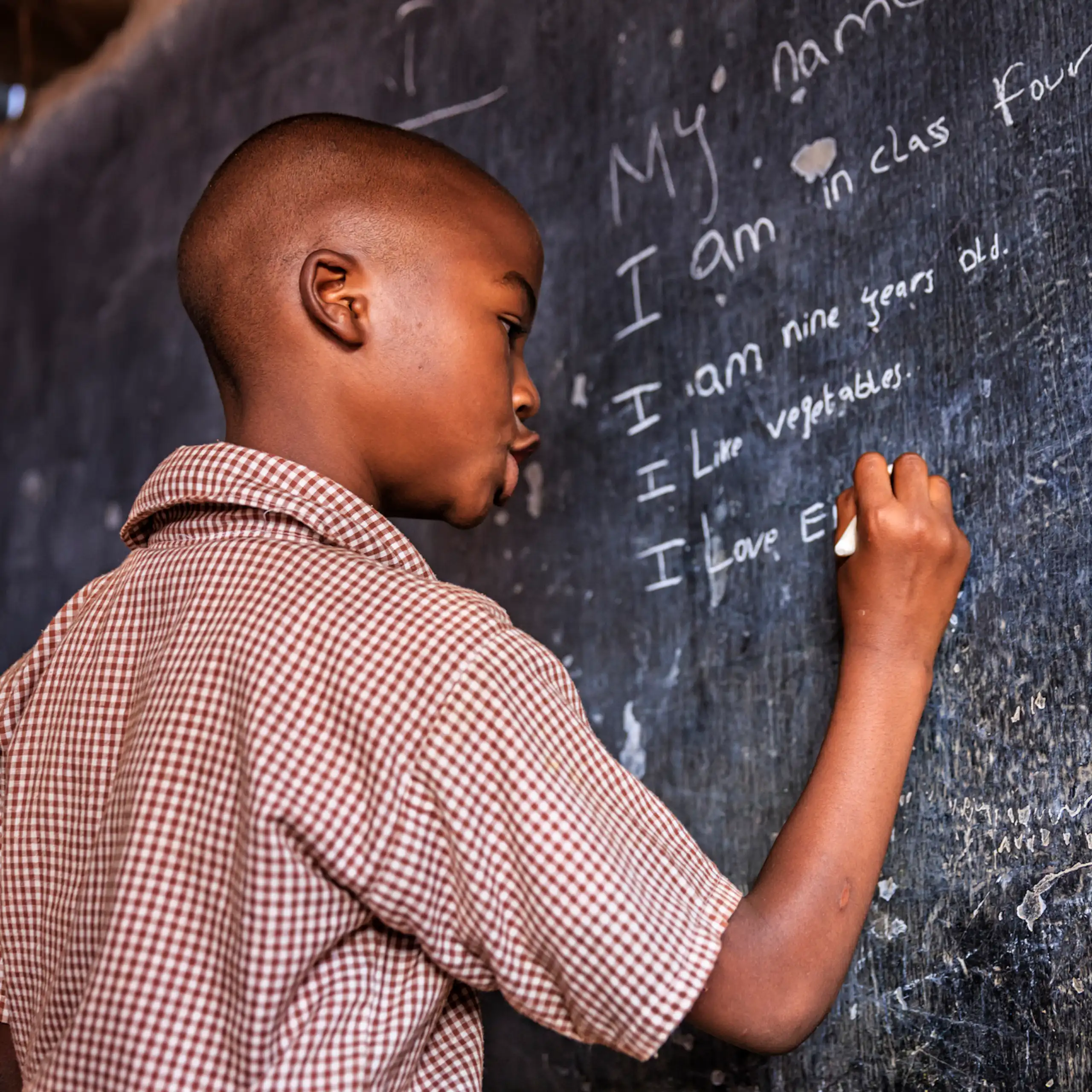 A boy writing on a chalkboard