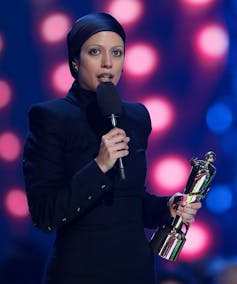 Una mujer sosteniendo un trofeo y un micrófono.