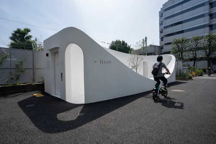 This toilet, in Tokyo, was designed by Japanese architect Sou Fujimoto. It is white with a beautiful curved exterior and an arched door.