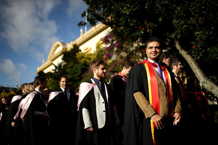 Students in graduation regalia lined up ahead of graduation ceremony